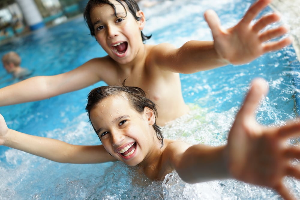 Happy little boys enjoying relaxing and splashing in water