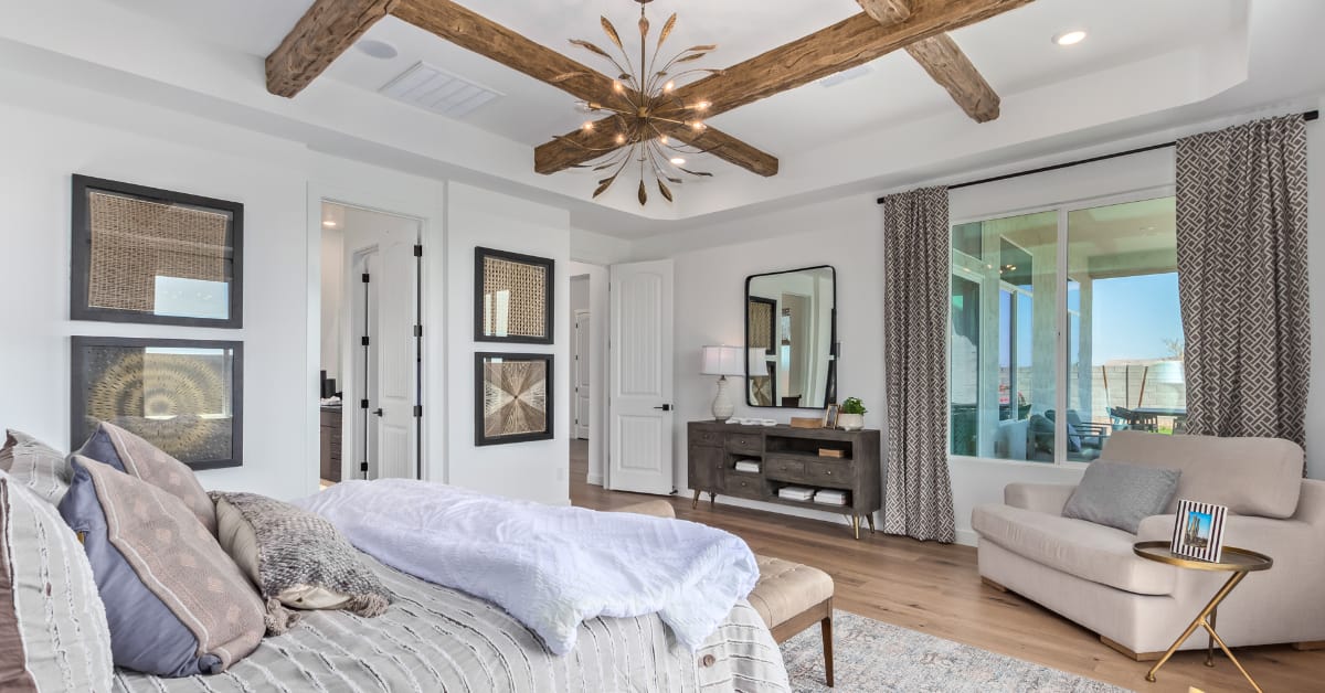 Trendy master bedroom featuring high ceilings, large windows, and faux beams.